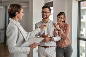 Young happy couple receiving new house keys from real estate agent.