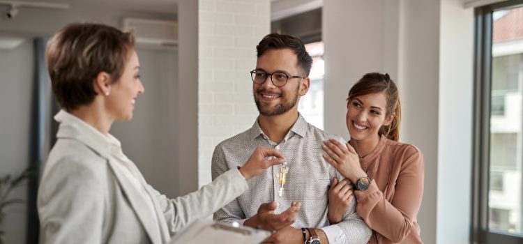 Young happy couple receiving new house keys from real estate agent.